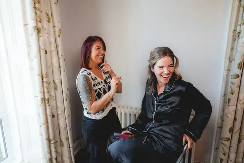 Bride laughing in a black robe during hair and makeup prep at Millbrook Lodge