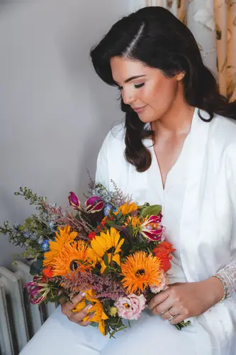 Bride holding her bouquet in soft window light during wedding morning preparations at Millbrook Lodge