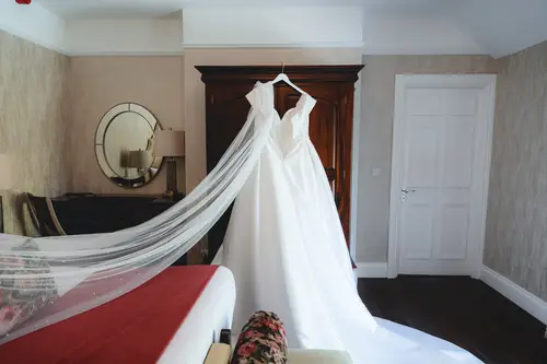 Wedding dress hanging in a bright bedroom at Millbrook Lodge on a sunny spring morning