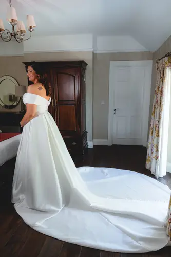 Bride in her wedding dress by the window during morning prep at Millbrook Lodge, Ballynahinch