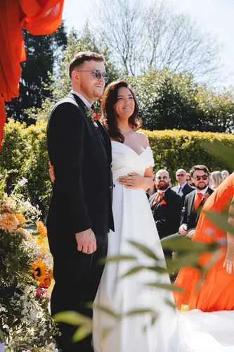 Bride and groom exchanging vows during a sunny outdoor ceremony at Millbrook Lodge, Ballynahinch