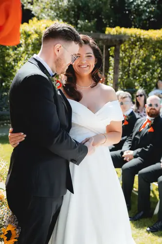 Couple exchanging vows during a sunny outdoor ceremony at Millbrook Lodge in Ballynahinch