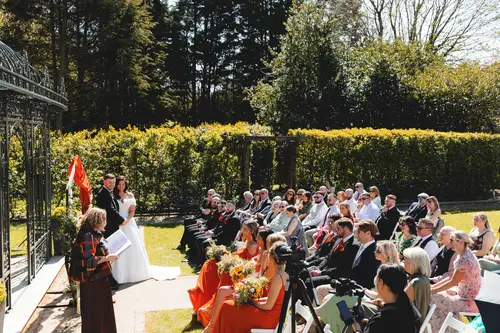 Outdoor ceremony vows in the gardens at Millbrook Lodge, Ballynahinch, with guests watching in sunny spring light