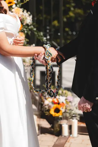 Couple holding hands during an outdoor handfasting ceremony in the spring sunshine at Millbrook Lodge, Ballynahinch