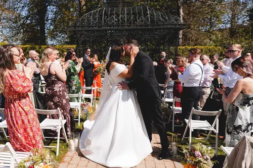 Bride and groom share their first kiss during a sunny outdoor ceremony at Millbrook Lodge, Ballynahinch