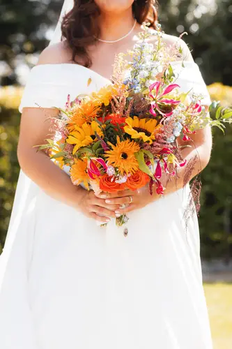 Bride holding a colourful sunflower bouquet in the spring sunshine at Millbrook Lodge, Ballynahinch