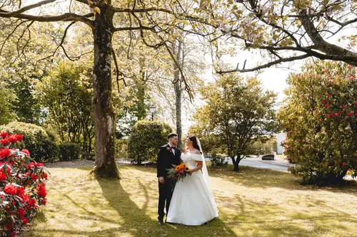 Bride and groom in a sunlit garden portrait at Millbrook Lodge, Ballynahinch