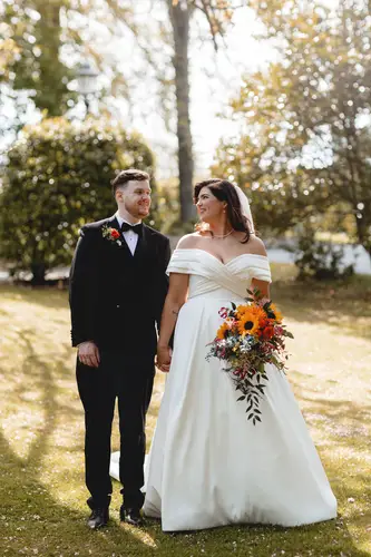 Bride and groom holding hands in golden garden light at Millbrook Lodge, Ballynahinch