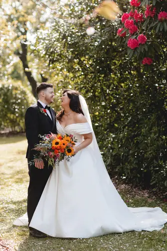 Bride and groom in a sunlit garden portrait at Millbrook Lodge, Ballynahinch, surrounded by spring flowers