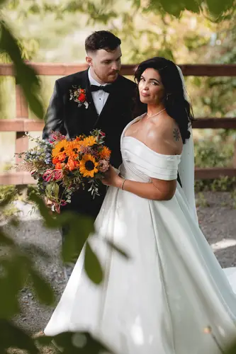 Bride and groom in black tie with a sunflower bouquet during sunny garden portraits at Millbrook Lodge, Ballynahinch