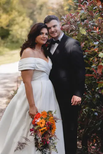 Newlyweds in black tie share a quiet garden portrait at Millbrook Lodge, Ballynahinch, with spring light and bouquet.