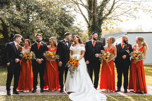 Bride, groom and wedding party laughing in sunny outdoor portraits at Millbrook Lodge, Ballynahinch