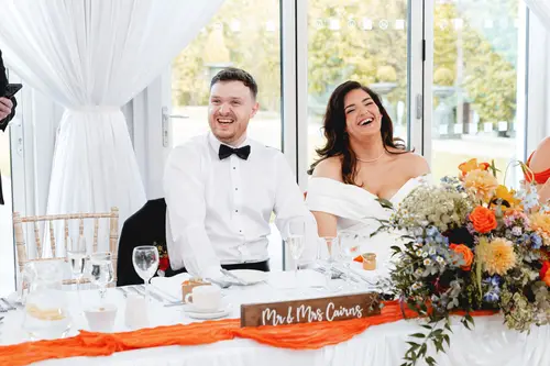 Bride and groom laughing at the top table during speeches at Millbrook Lodge, Ballynahinch