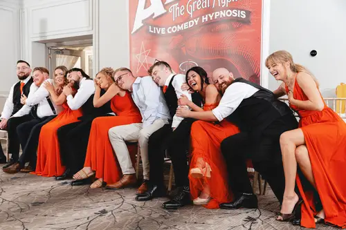 Bridal party laughing during reception games at Millbrook Lodge, with orange bridesmaid dresses and a lively evening atmosphere