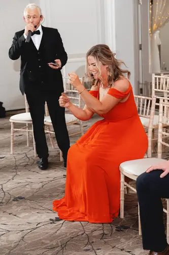 Wedding guests laughing during party games at Millbrook Lodge reception in Ballynahinch