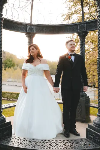 Newlyweds holding hands beside the gazebo at Millbrook Lodge, Ballynahinch, in soft golden hour light
