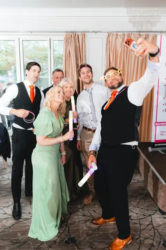Wedding guests posing with photo booth props during the evening reception at Millbrook Lodge, Ballynahinch