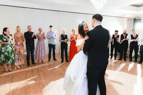 Bride and groom share their first dance as guests clap around the floor at Millbrook Lodge