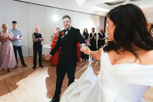 First dance at Millbrook Lodge in Ballynahinch with guests gathered around the warm-lit dance floor