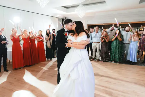 Newlyweds kiss during their first dance at Millbrook Lodge as guests cheer with glow sticks