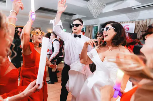 Newlyweds dancing with glow sticks and sunglasses during the evening reception at Millbrook Lodge