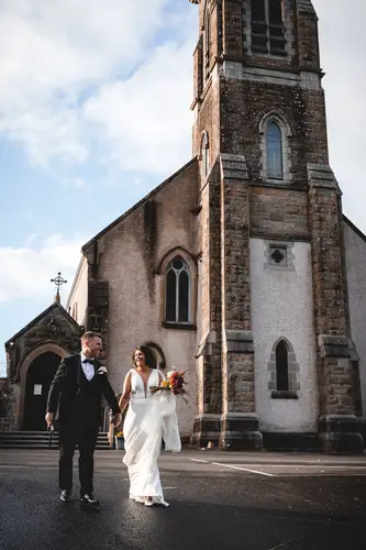 Bride and groom walking outside a church in Cavan after their Cavan Crystal wedding in soft daylight
