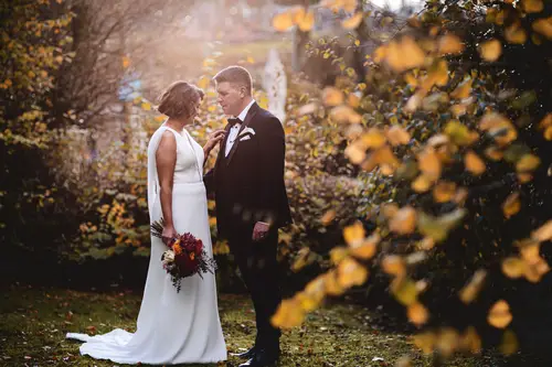 Bride and groom in a backlit garden portrait at Cavan Crystal, Cavan, with autumn foliage and a wedding bouquet