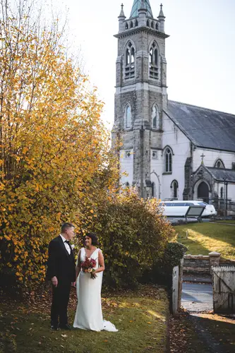 Bride and groom portrait outside a Cavan church with autumn foliage and soft natural light