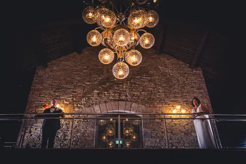 Bride and groom portrait on the balcony at Cavan Crystal, with warm chandelier light and a stone wall backdrop