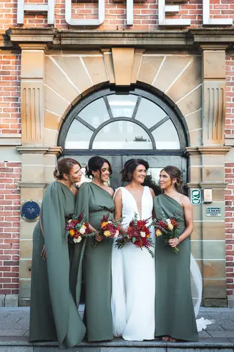 Bride and bridesmaids with bouquets at the arched entrance of Cavan Crystal in County Cavan