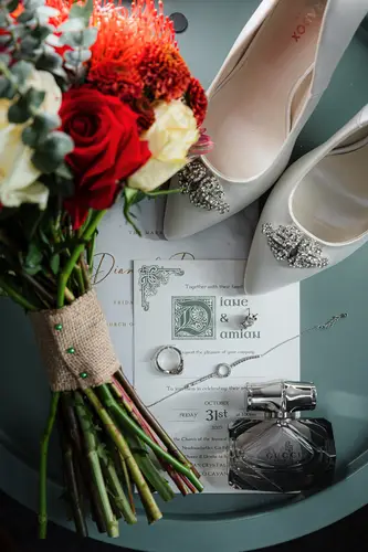 Bridal details flat lay with shoes, bouquet, rings, invitation and perfume on a wedding morning at Cavan Crystal