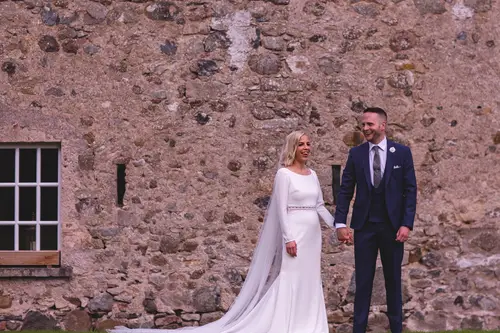 Bride and groom holding hands by the stone wall at Old Rectory, Killyman, in soft natural light