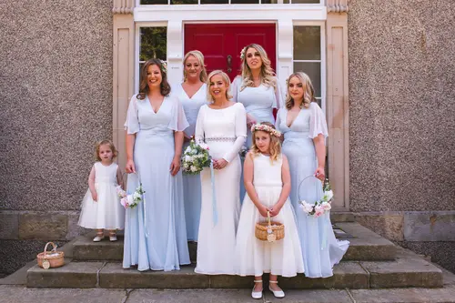 Bride, bridesmaids and flower girls on the doorway steps at Old Rectory, Killyman, gathered by the red door in natural light