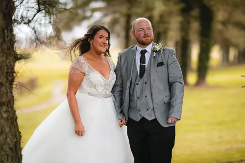 Bride and groom holding hands for relaxed couple portraits under trees at Redcastle Hotel in Moville