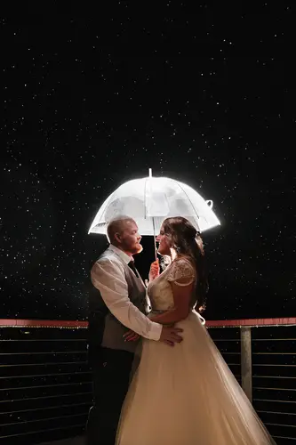 Bride and groom in a backlit night portrait under an umbrella in the rain at Redcastle Hotel, Moville