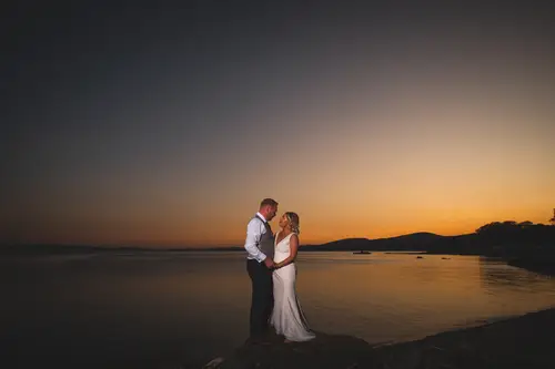 Bride and groom silhouetted at sunset by the waterfront at Redcastle Hotel in Moville, County Donegal