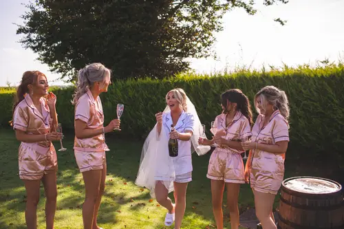 Bride and bridesmaids in robes sharing champagne in the garden at Redcastle Hotel, Moville on the wedding morning