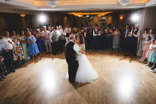 First dance at Redcastle Hotel in Moville, with the couple in a warm spotlight as guests gather around the dance floor