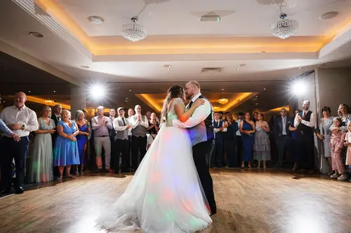 Bride and groom sharing their first dance at Redcastle Hotel in Moville, with guests watching under warm party lights