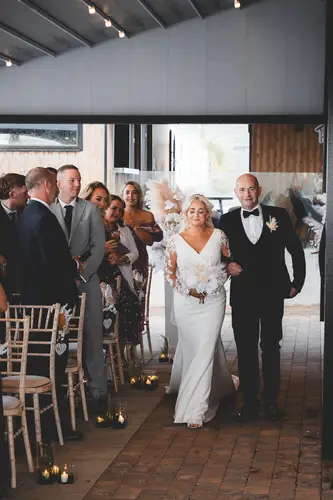 Bride walking down the aisle during an indoor ceremony at Rossharbour Resort, with guests watching in soft natural light.