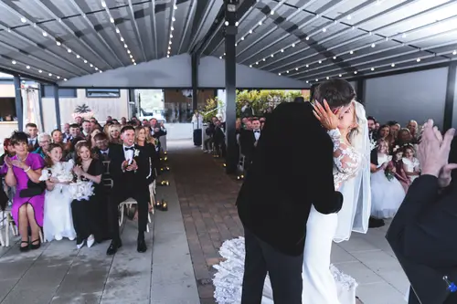 Bride and groom share their first kiss during a natural light ceremony on the covered terrace at Rossharbour Resort.