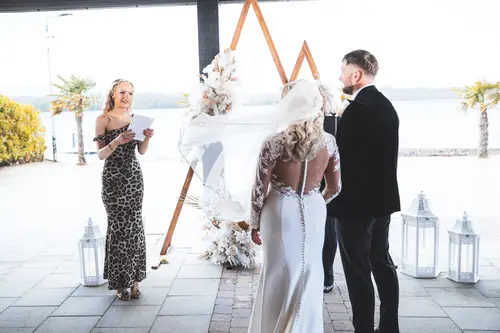 Outdoor wedding vows at Rossharbour Resort, Lough Erne, with an officiant, floral arch and soft backlit waterfront setting