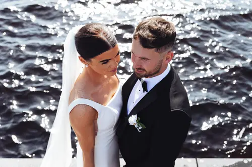 Sunlit bride and groom portrait by the water at Rossharbour Resort, Lough Erne, with veil and black tie styling