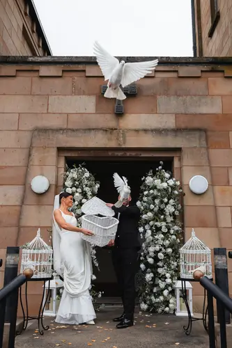 Bride and groom releasing doves beneath a floral arch at Rossharbour Resort in County Fermanagh