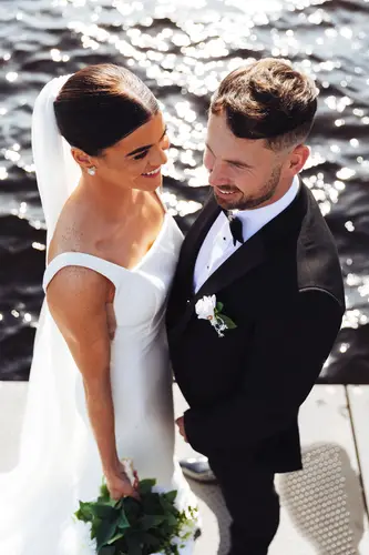 Sunlit bride and groom portrait by the water at Rossharbour Resort, Lough Erne, with bouquet and black tie styling.