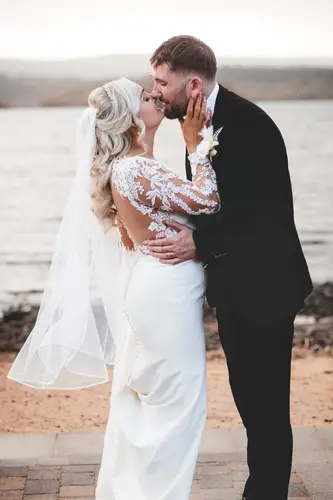 Bride and groom sharing a kiss by the water during couple portraits at Rossharbour Resort, Lough Erne