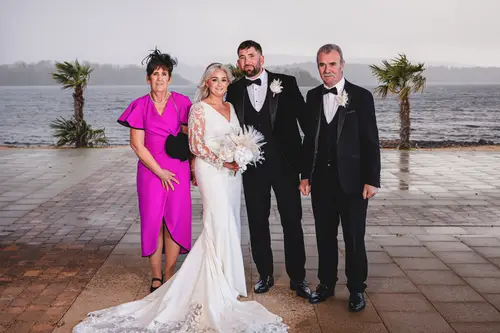 Family wedding portrait with the couple and parents by the waterfront at Rossharbour Resort, County Fermanagh