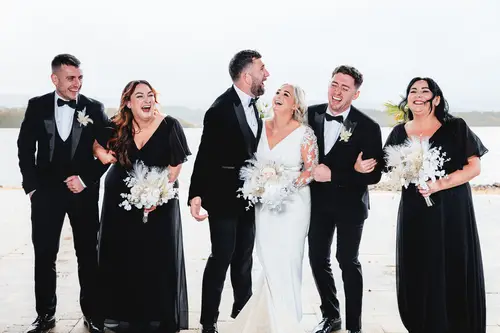 Bridal party walking by the water at Rossharbour Resort, Lough Erne, with candid laughter in natural light
