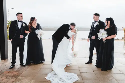 Bride and groom share a dipped kiss with their bridal party by the lake at Rossharbour Resort, Lough Erne
