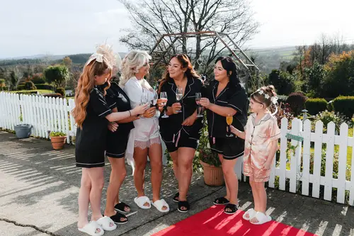 Bridal party in pajamas with a flower girl during relaxed wedding morning drinks at Rossharbour Resort, Lough Erne